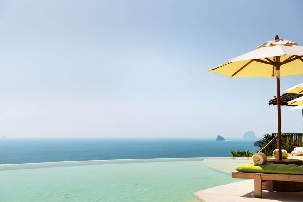 infinity pool with parasol and sun beds at ocean